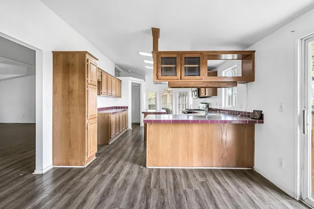 a kitchen with stainless steel appliances granite countertop a stove top oven a sink dishwasher and a microwave oven with wooden floor