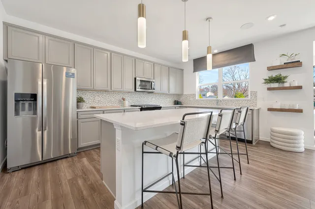 a kitchen with stainless steel appliances granite countertop a refrigerator a sink dishwasher a stove and white cabinets with wooden floor