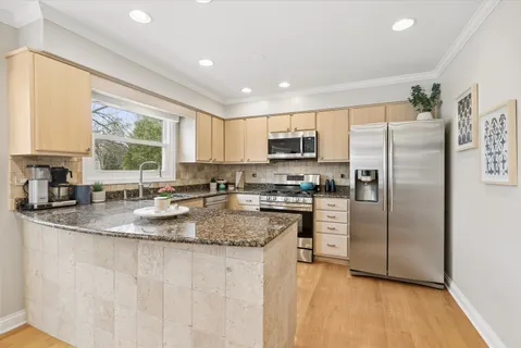 a kitchen with stainless steel appliances granite countertop a refrigerator a sink a stove a microwave a center island and cabinets
