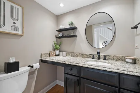 a bathroom with a granite countertop sink a mirror and a toilet