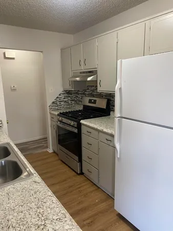 a kitchen with a refrigerator sink stove and cabinets