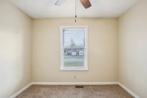 an empty room with a window and a ceiling fan