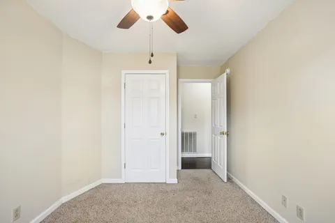an empty room with chandelier fan and windows