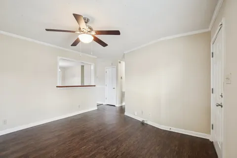 a view of empty room with wooden floor and fan