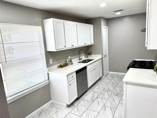 a kitchen with white cabinets and sink