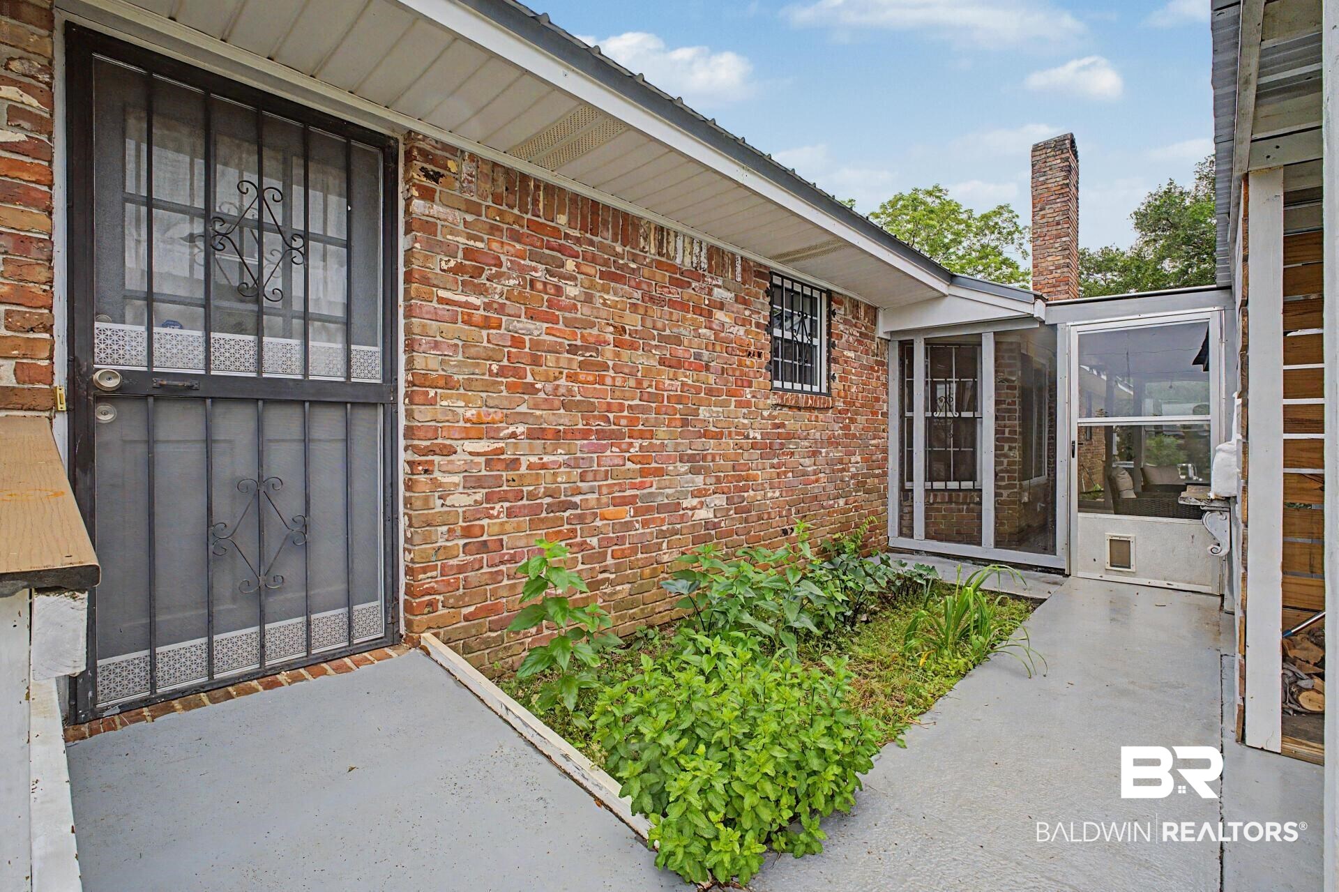 3791 Robinsonville Road Atmore, AL 36502 - Photo 13 of 47 Brick exterior featuring a screened entrance, security door, and window bars