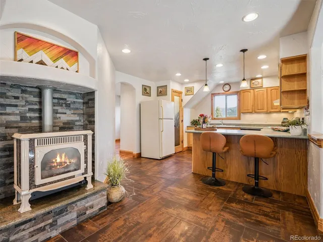 a living room with stainless steel appliances kitchen island granite countertop furniture and a fireplace