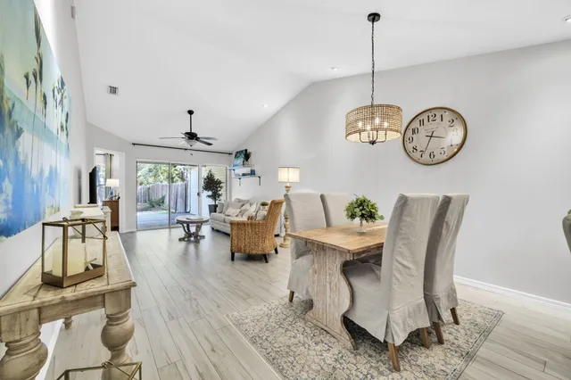 a dining room with wooden floor a chandelier a wooden table and chairs