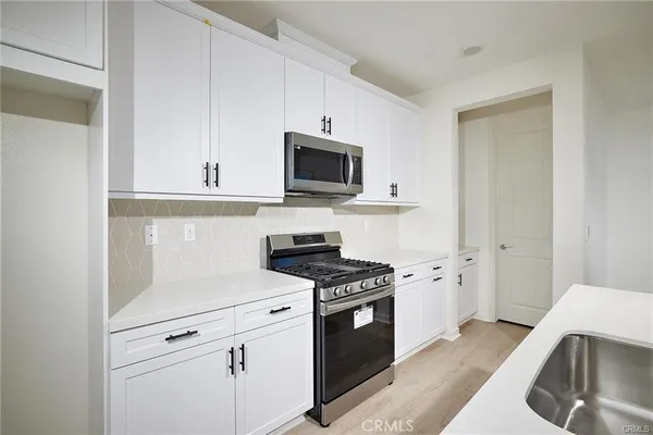 a kitchen with stainless steel appliances white cabinets and a stove a sink