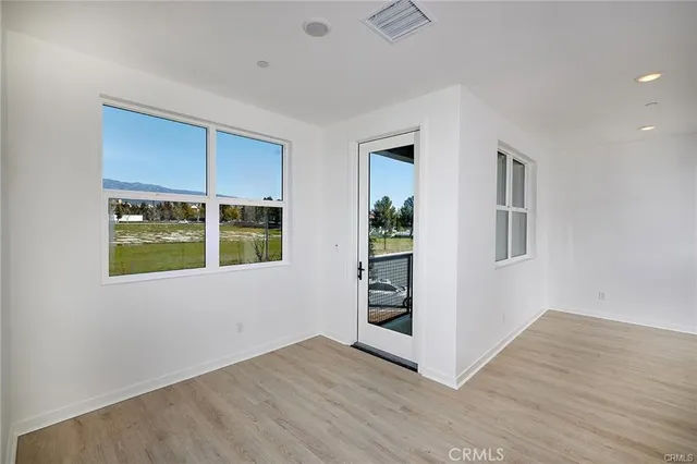 a view of an empty room with a window and wooden floor