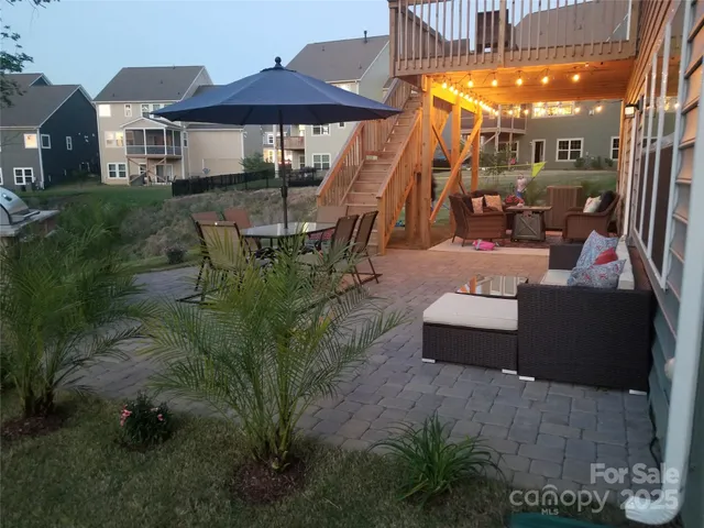 a view of a patio with couches table and chairs under an umbrella with a small yard