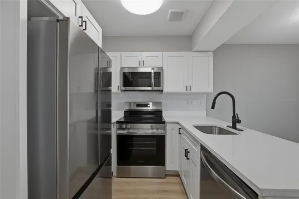 a kitchen with stainless steel appliances a stove microwave and sink