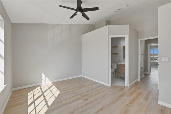 a view of empty room with wooden floor and fan