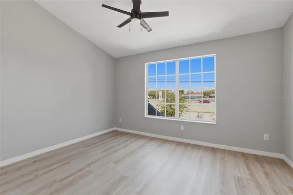 an empty room with wooden floor and windows