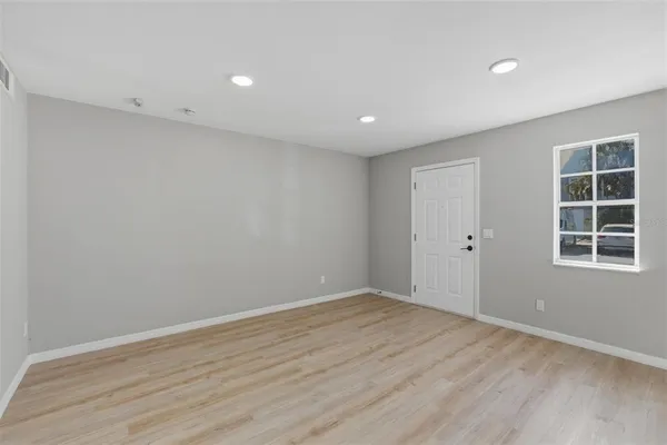 a view of empty room with wooden floor and windows