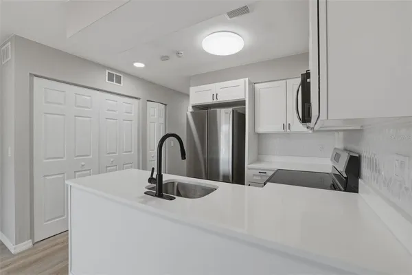 a kitchen with stainless steel appliances granite countertop a sink and white cabinets