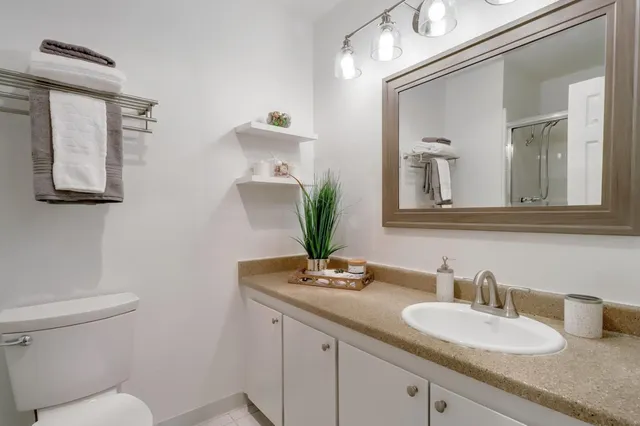 a bathroom with a granite countertop toilet sink and mirror