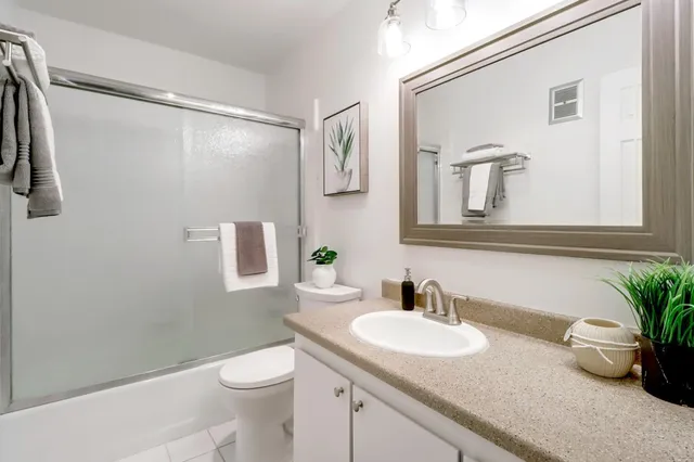 a bathroom with a granite countertop sink a toilet and a mirror