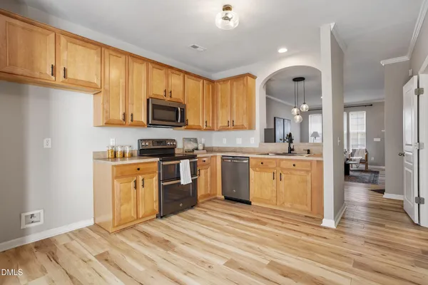 a kitchen with stainless steel appliances granite countertop a stove top oven a sink dishwasher and a refrigerator with wooden floor