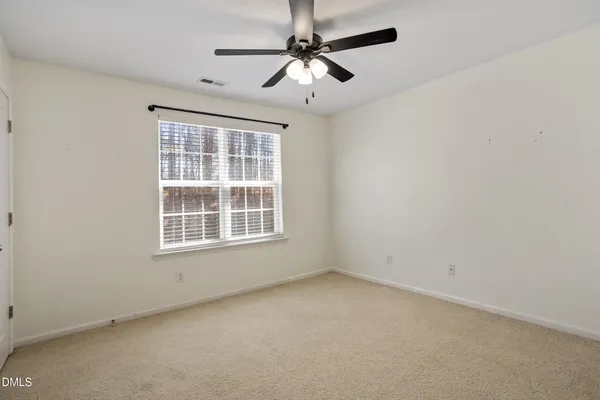 an empty room with a fan & a ceiling fan