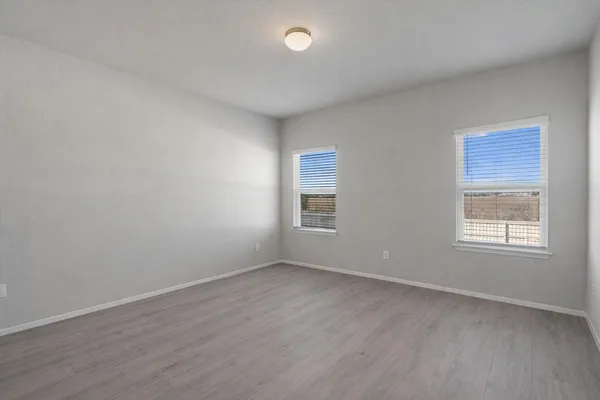 a view of an empty room with wooden floor and closet