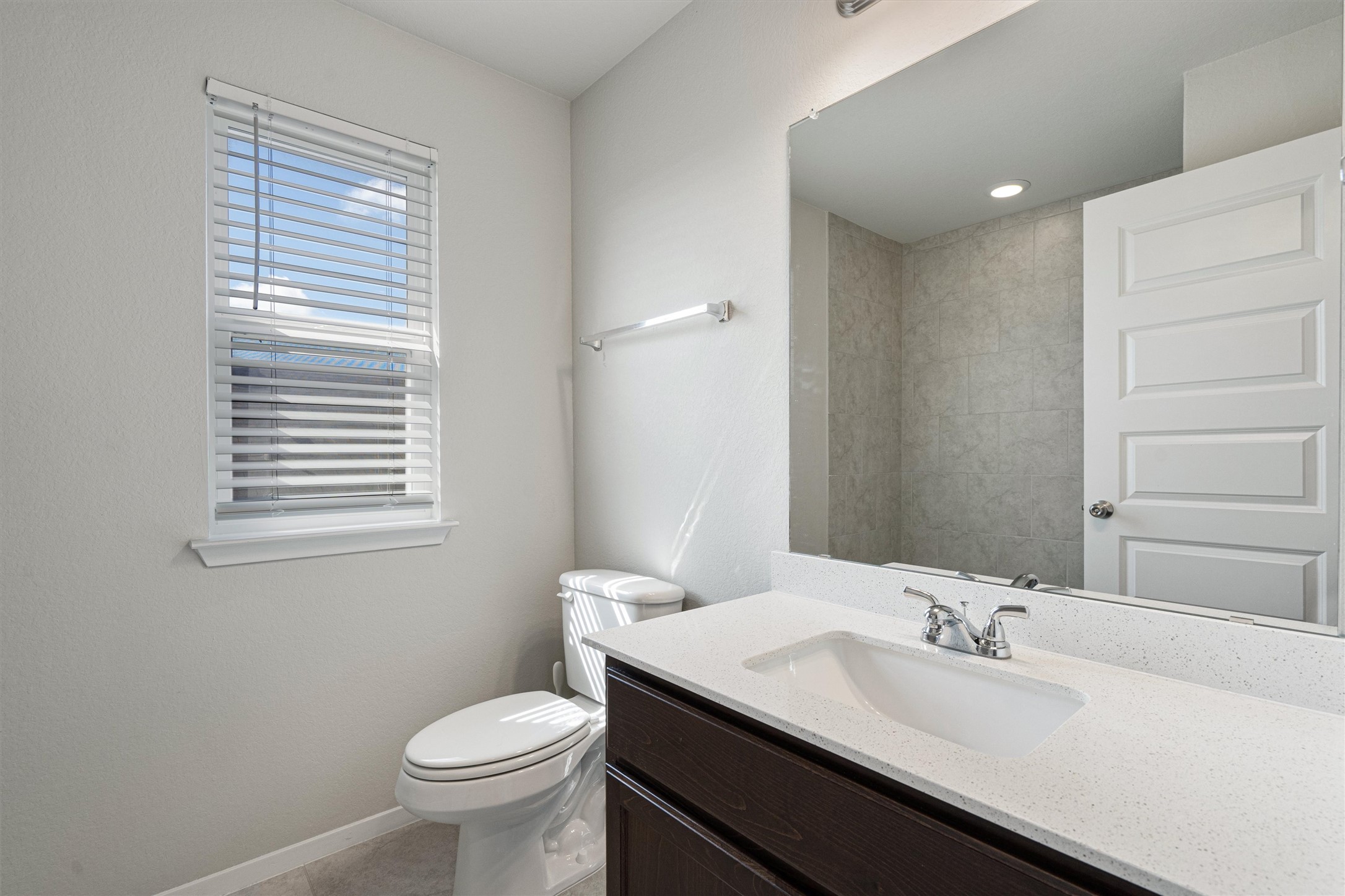 2711 Winding Creek Road Kyle, TX 78640 - Photo 29 of 33 a bathroom with a granite countertop toilet a sink and a mirror