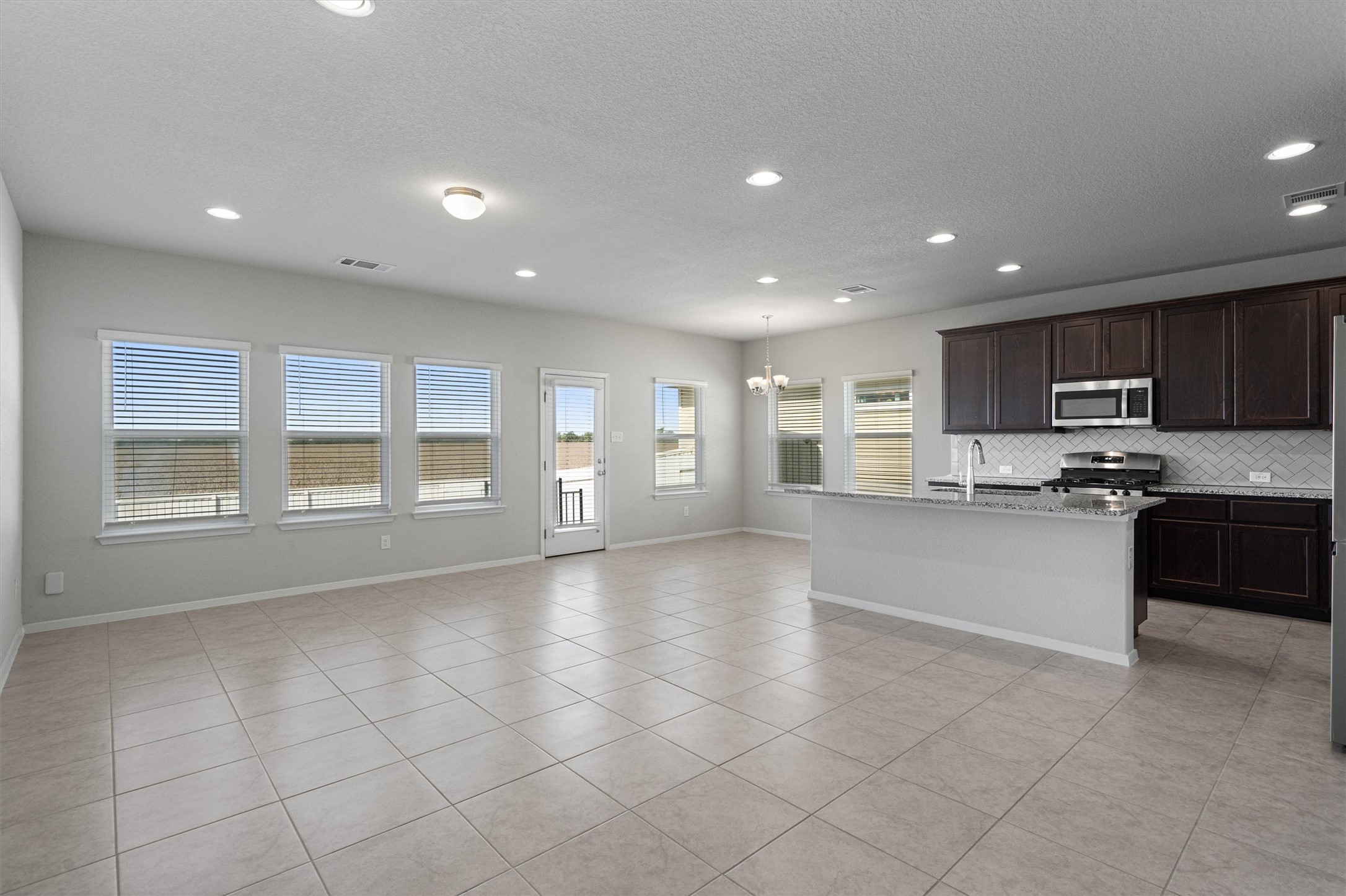 2711 Winding Creek Road Kyle, TX 78640 - Photo 7 of 34 a large kitchen with granite countertop a large counter top stainless steel appliances and cabinets