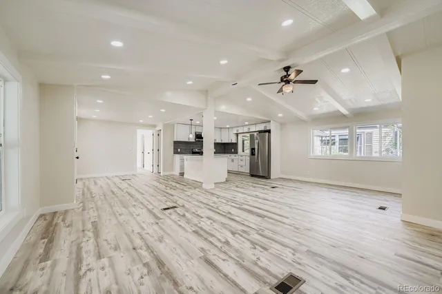a view of an empty room with wooden floor and a ceiling fan