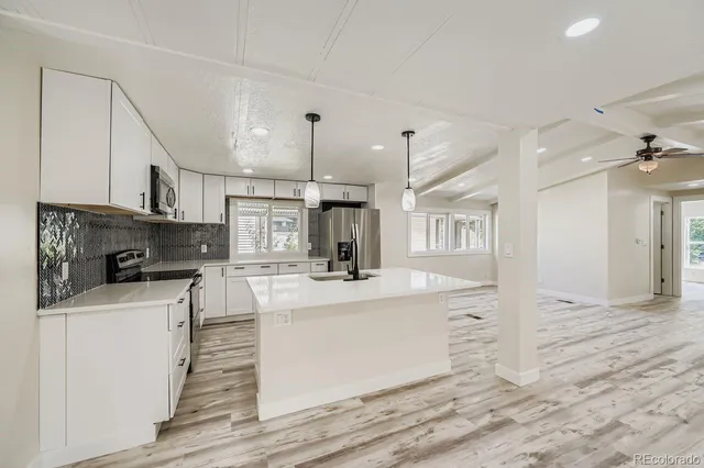 a kitchen with kitchen island a stove a sink and a refrigerator