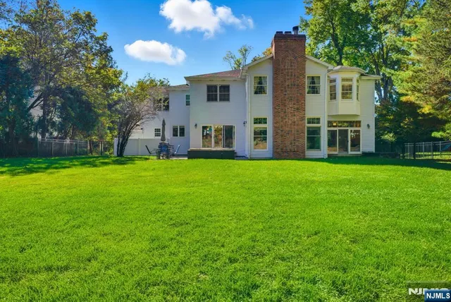 a view of a house with a big yard and large trees