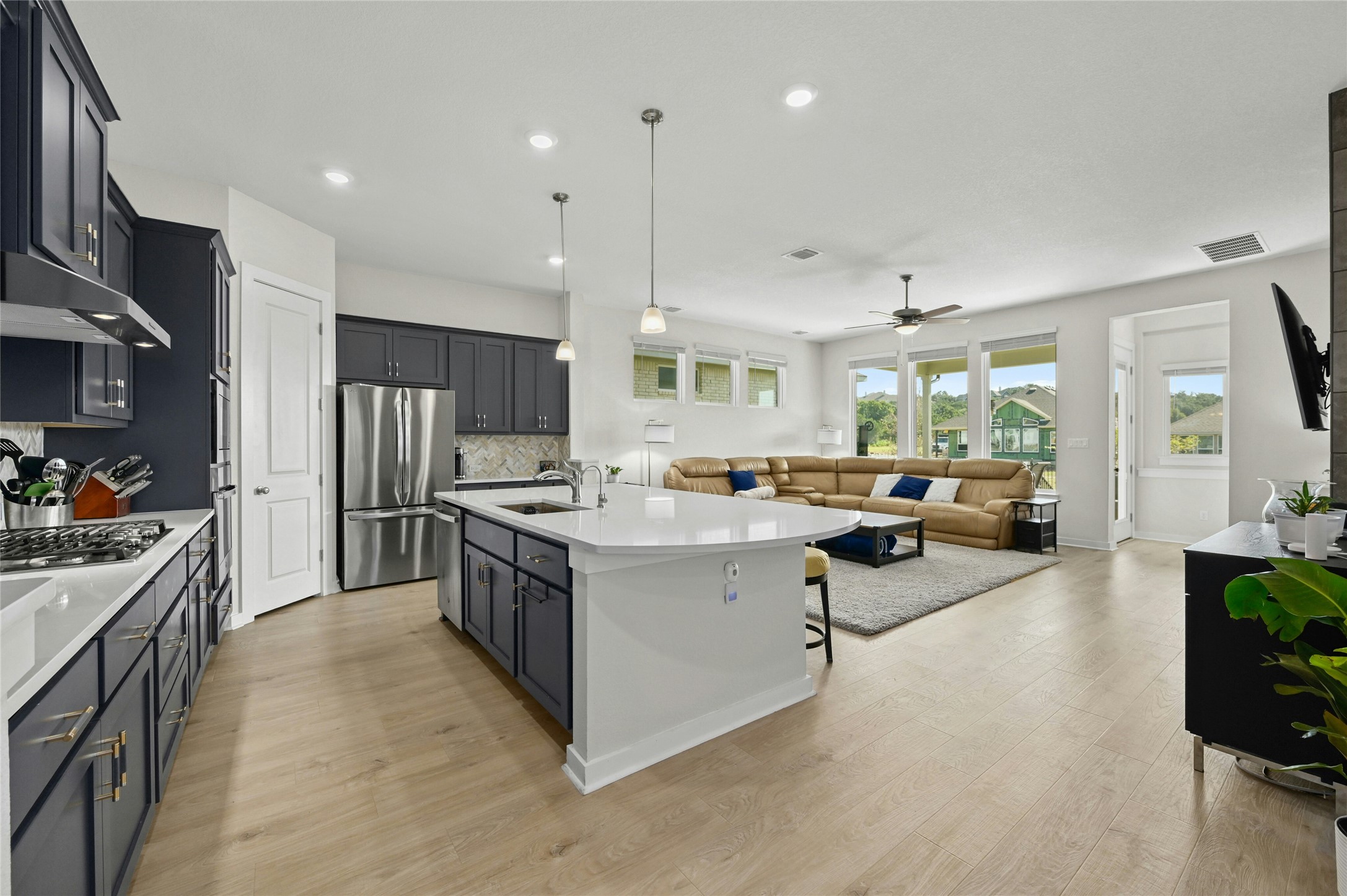 916 Leaning Oak Lane Georgetown, TX 78628 - Photo 5 of 32 Kitchen featuring breakfast bar with a sink, hanging light fixtures, stainless steel appliances, recessed lighting, and light wood-style flooring