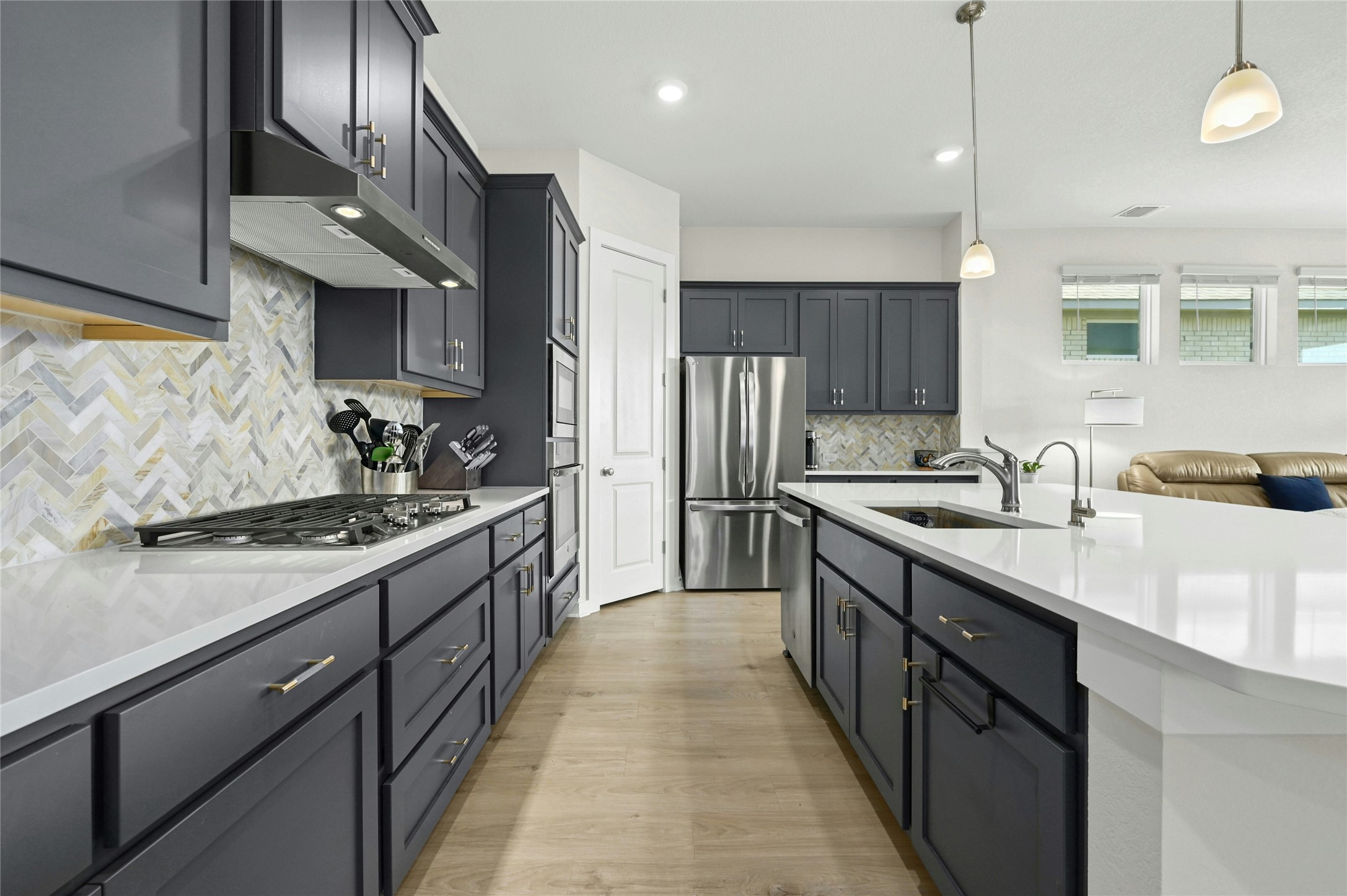 916 Leaning Oak Lane Georgetown, TX 78628 - Photo 6 of 32 Kitchen with stainless steel appliances, pendant lighting, light wood finished floors, under cabinet range hood, and light stone counters