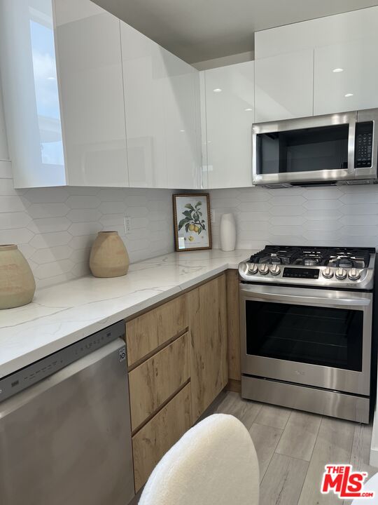 124 South Croft Avenue, Unit 403 Los Angeles, CA 90048 - Photo 13 of 31 a kitchen with stainless steel appliances a stove a microwave and cabinets