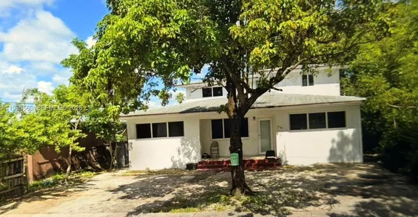 a front view of a house with a tree