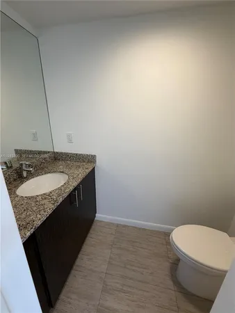 a bathroom with a granite countertop sink and a toilet