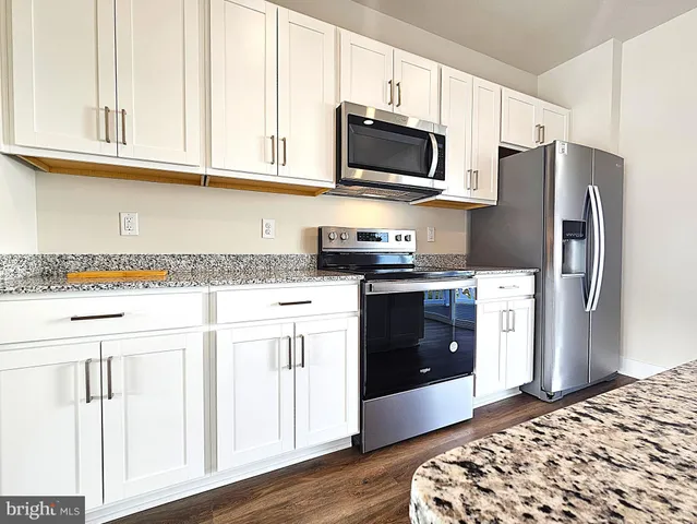 a kitchen with stainless steel appliances granite countertop a refrigerator stove a sink and dishwasher with wooden floor