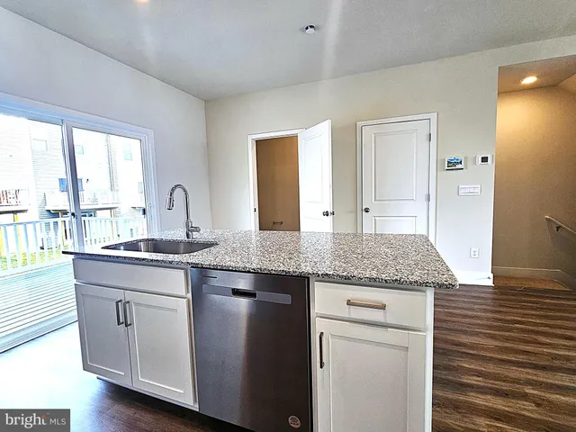 a open kitchen with granite countertop a sink and dishwasher with wooden floor