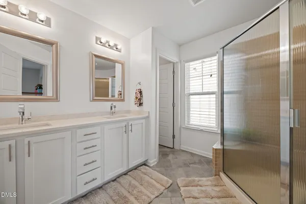 a spacious bathroom with double vanity a mirror a shower and a vanity