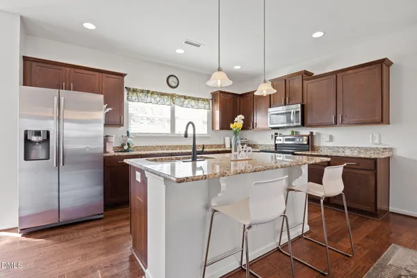 a kitchen with stainless steel appliances granite countertop a sink a stove a refrigerator cabinets and a center island