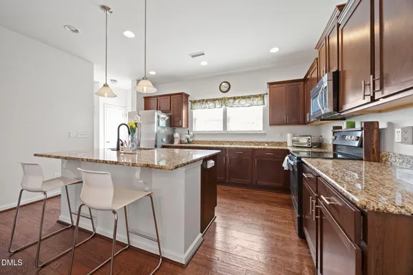 a kitchen with stainless steel appliances granite countertop a sink a stove and a refrigerator