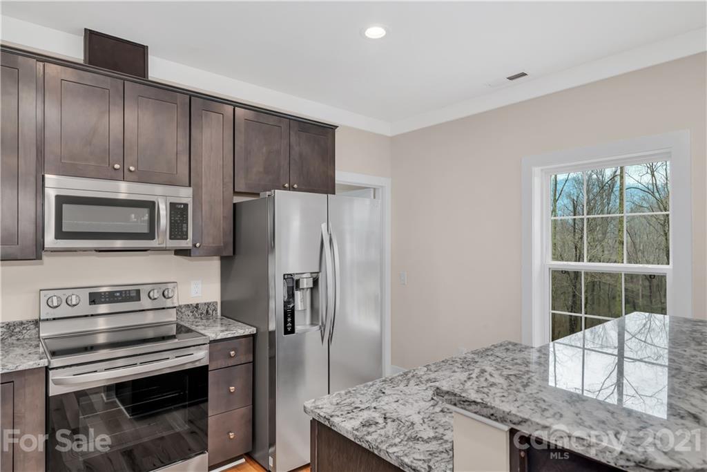 357 Ridge View Drive, Unit 4 Clyde, NC 28721 - Photo 9 of 20 a kitchen with kitchen island granite countertop a stove refrigerator and microwave