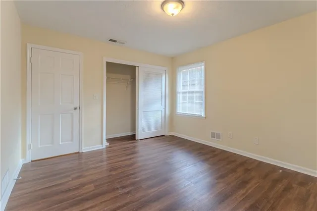an empty room with wooden floor and windows