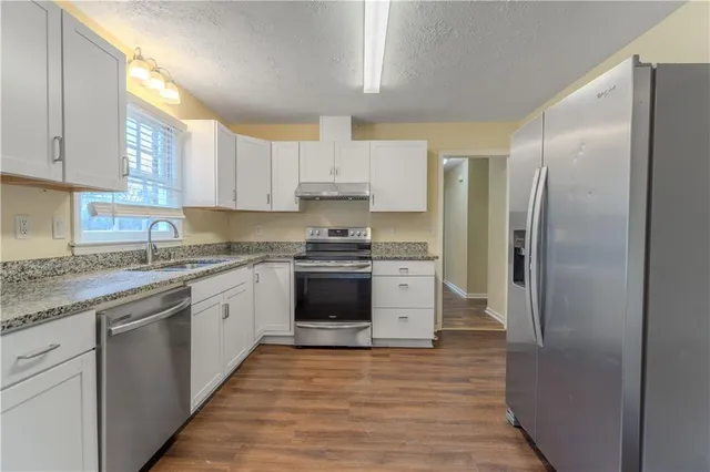 a kitchen with stainless steel appliances granite countertop a refrigerator and a stove top oven