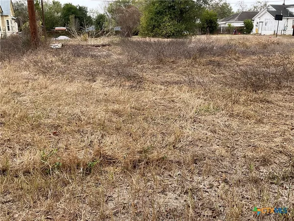 a view of a dry yard with wooden fence