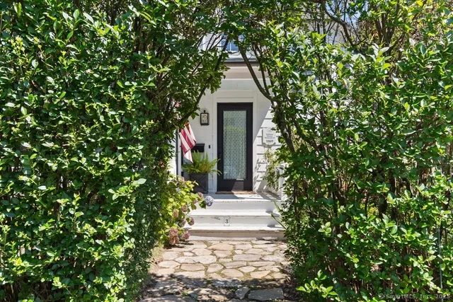 a front view of a house with a yard and potted plants
