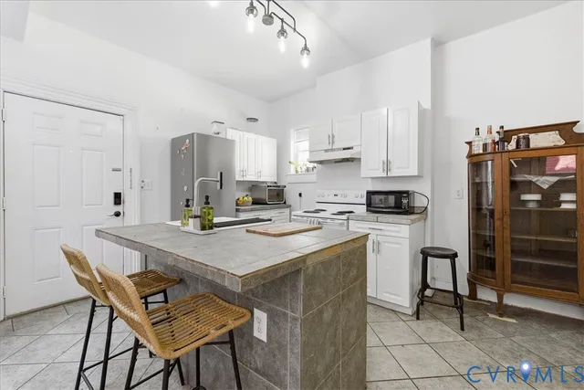 a kitchen with stainless steel appliances kitchen island granite countertop a table chairs and a refrigerator