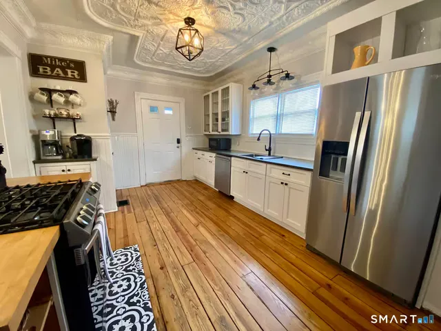 a kitchen with stainless steel appliances a refrigerator a sink a stove and white cabinets