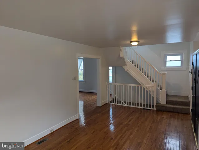 a view of an empty room with window and wooden floor