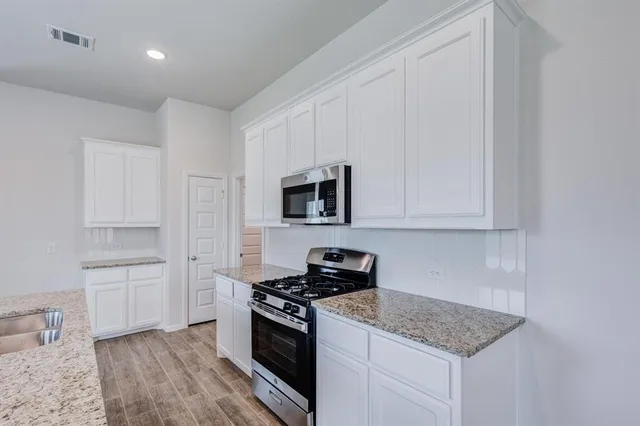 a kitchen with granite countertop a sink dishwasher a stove and a refrigerator