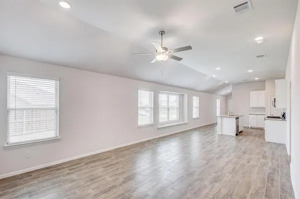 a view of an empty room with a window and wooden floor